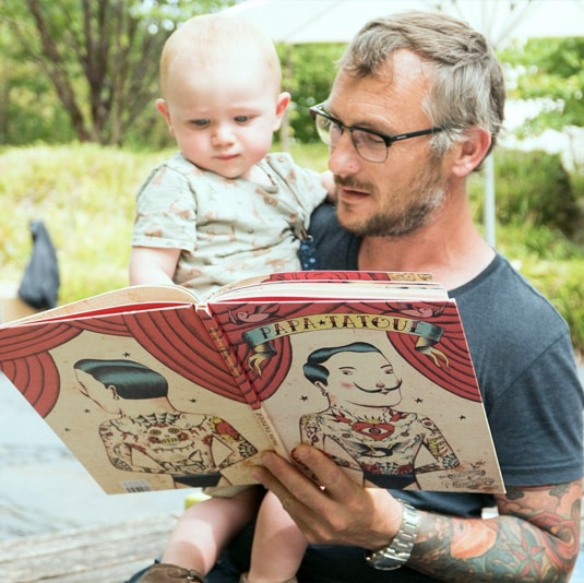 Papa sui lit un livre à son bébé